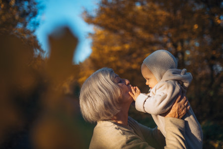 Grandma holding baby in warm embrace during fall season.