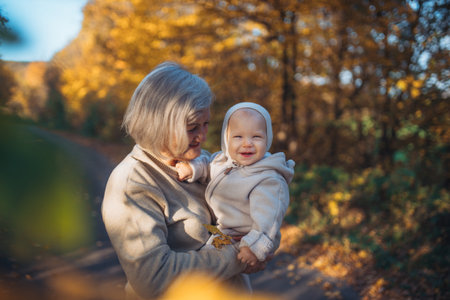 Grandma holding baby in warm embrace during fall season.の写真素材