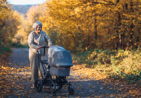 Grandma with grandbaby in stroller on walk in autumn nature.の写真素材