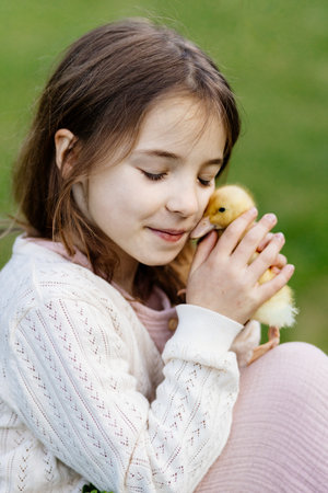 Young girl in garden playing with baby duckling.