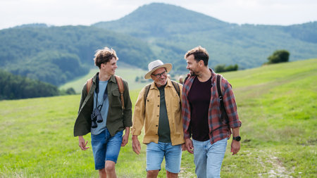 Grandfather, father and teen boy hiking togeter in nature, spending time together during weekend.