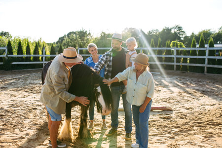 Farmer family standing in horse paddock with pony.の写真素材