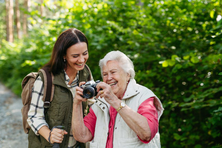 Elderly mother and daughter admire wildlife during forest walk.