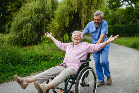 Male home nurse pushing elderly woman in wheelchair, having fun.の写真素材