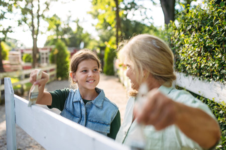 Young girl helping on farm, painting fence.の写真素材
