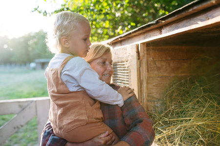 Grandmother showing farm animals to grandson.の写真素材