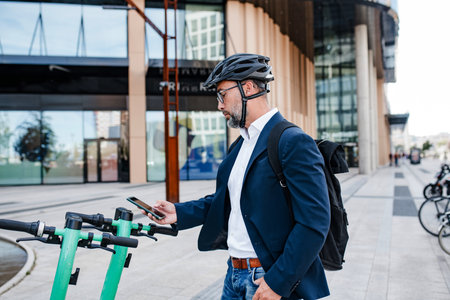 Businessman unlocking electric scooter with smartphone.の写真素材