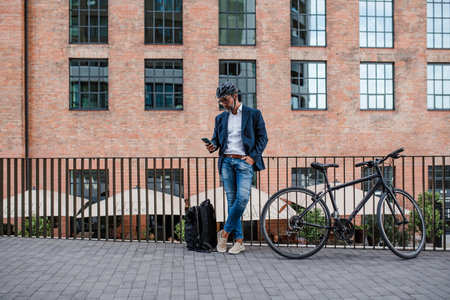 City commuter riding bike from work, reading text message on phone.の写真素材
