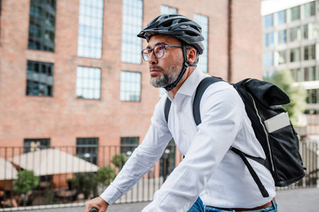 Man riding bike to work in city with helmet and backpackの写真素材