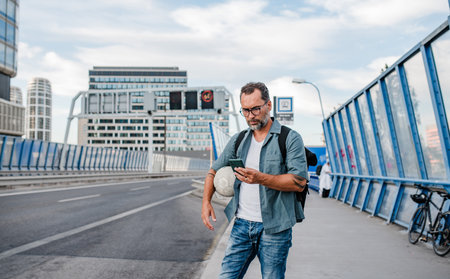 Mature man waiting for bus, texting on smartphone.の写真素材