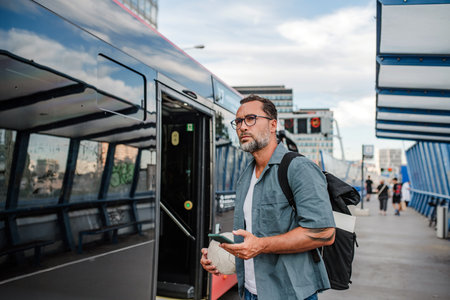 Man boarding bus, holding sport ball and phone.の写真素材
