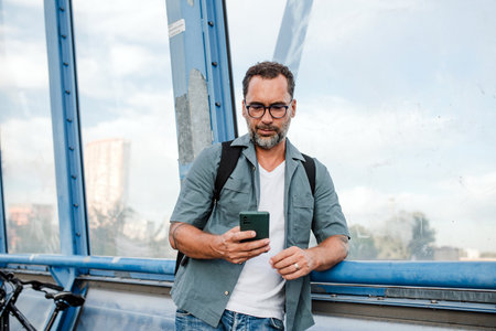Bearded man using phone while waiting.