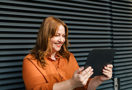Plus size woman holding tablet, black background.