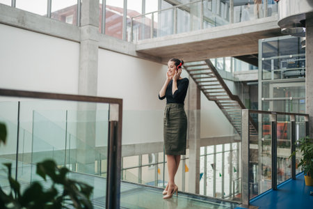 Businesswoman with headphones standing in modern openspace office building.の写真素材