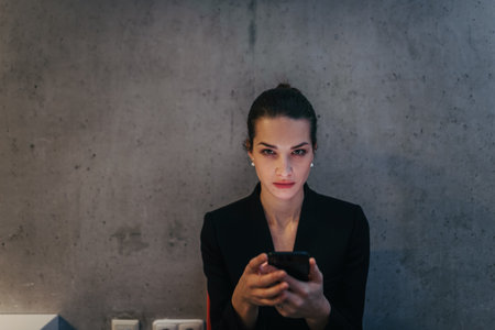 Portrait of young businesswoman reading email on smartphone.の写真素材