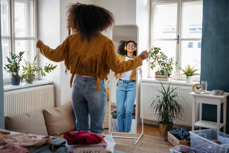 Young woman dancing in front of mirror with headphones.の写真素材