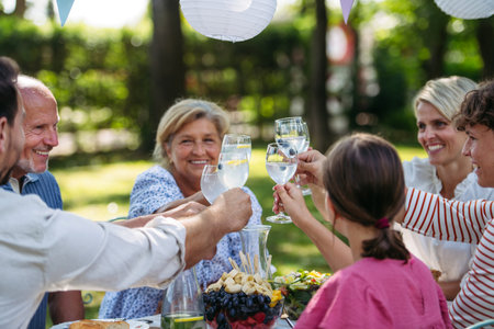 Multigenerational family toasting during outdoor barbecue party.の写真素材