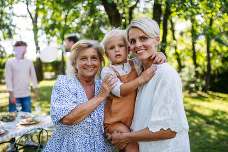 Smiling grandmother talking with her daughter, holding grandchild, family gathering.の写真素材