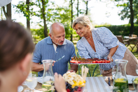 Senior woman serving grilled food during family grill party.の写真素材