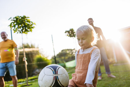 Little boy playing football with father and grandfather in backyard.の写真素材