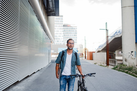 Man riding bike to work in city with helmet and backpackの写真素材