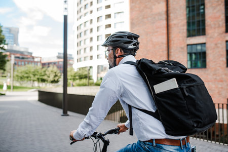 City commuter riding bike to office, wearing backpack and helmet.の写真素材