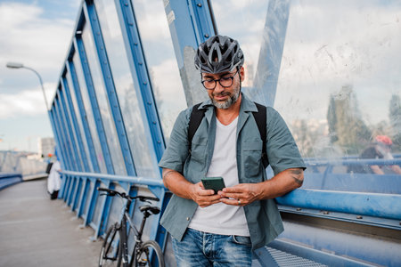 Bearded cyclist using phone while waiting for bus.の写真素材