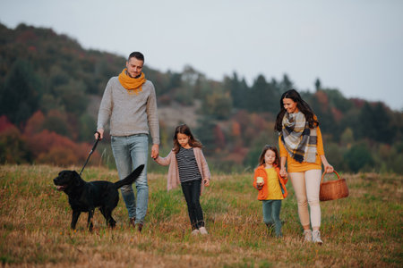 Happy young family with two children in autumn nature at sunset.の写真素材