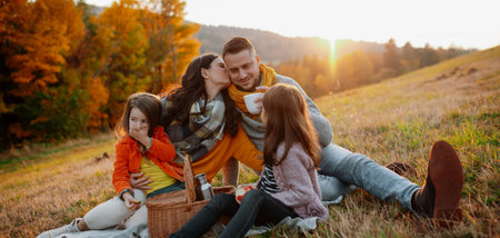 Parents with young children sitting outdoors in autumn light.の写真素材