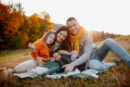 Parents with young children sitting outdoors in autumn light.の写真素材