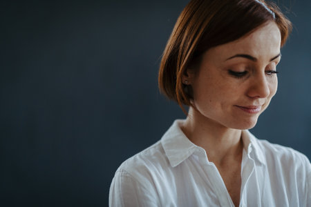 A portrait of young woman standing against dark background.の写真素材