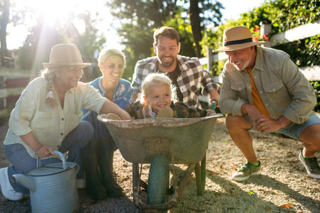 Joyful child sitting in wheelbarrow, family portrait on farm.の写真素材