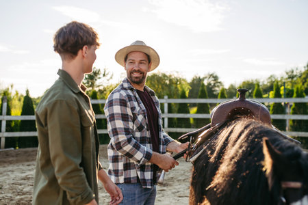 ather and son preparing horse for riding.の写真素材