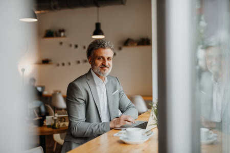 Businessman working remotely from coffee shop, using laptop.の写真素材