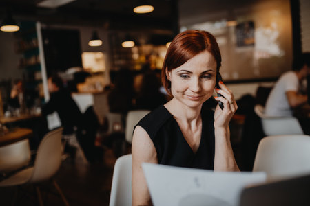 A portrait of woman working remotely from coffee shop, using laptop.の写真素材