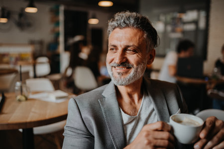 Businessman working remotely from coffee shop, using laptop.の写真素材