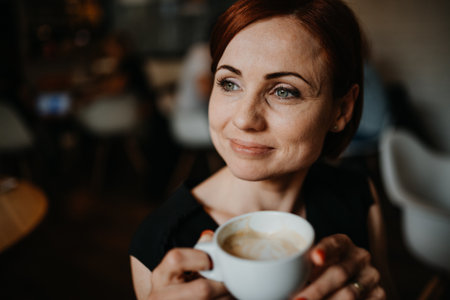 Portrait of woman sitting in a cafe, holding a cup of coffee.の写真素材