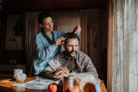 Woman cutting husbands hair at home due to financial hardship.の写真素材