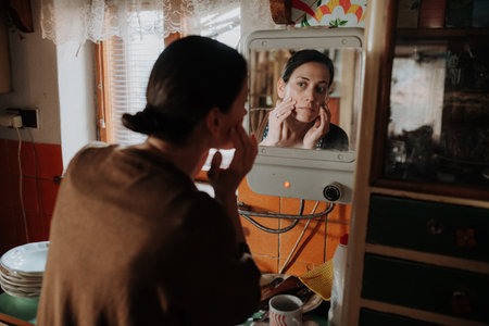 Tired woman examining her tired skin in old mirror.の写真素材