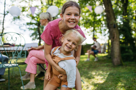Sister playing with her toddler brother at family garden party.の写真素材