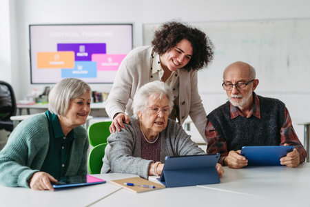Group of seniors learning digital skills with tutor support in community center.の写真素材
