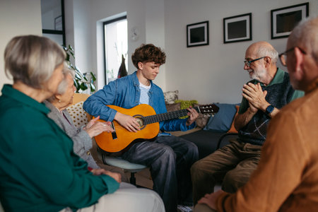 Group of elderly people singing together with young volunteer playing guitar.の写真素材