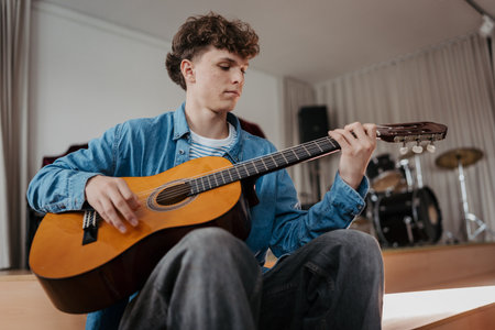 Teenage boy playing acoustic guitar in school music room.の写真素材