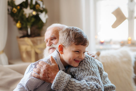 Boy spending Christmas time with senior grandfather indoors at home.の写真素材