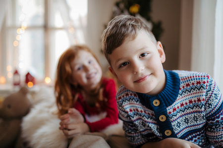 Small girl and boy in pajamas indoors at home at Christmas, playing.の写真素材