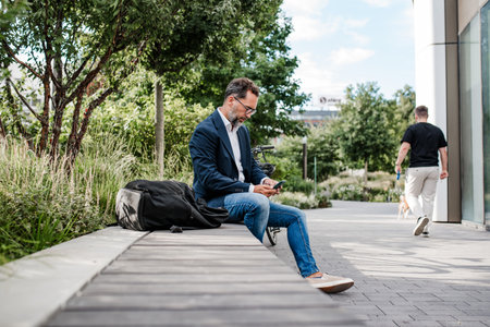 Manager working in urban park, making phone call and typing on laptop.の写真素材