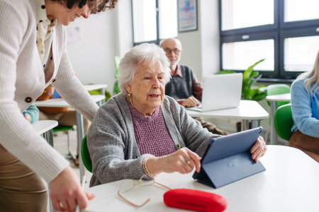 Elderly woman learning digital skills with tutor help.の写真素材