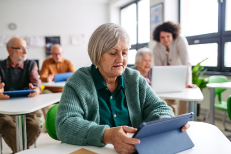 Elderly woman learning digital skills with tutor help.の写真素材