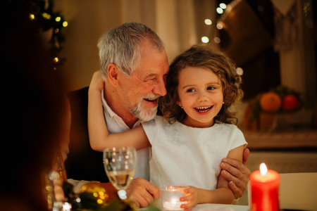 Grandfather and granddaughter holding candle during Christmas celebration.の写真素材