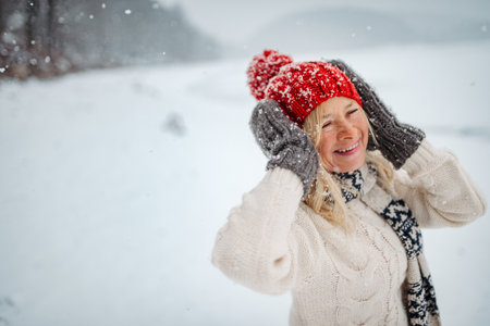 Senior woman enjoying snowfall in winter landscape.の写真素材